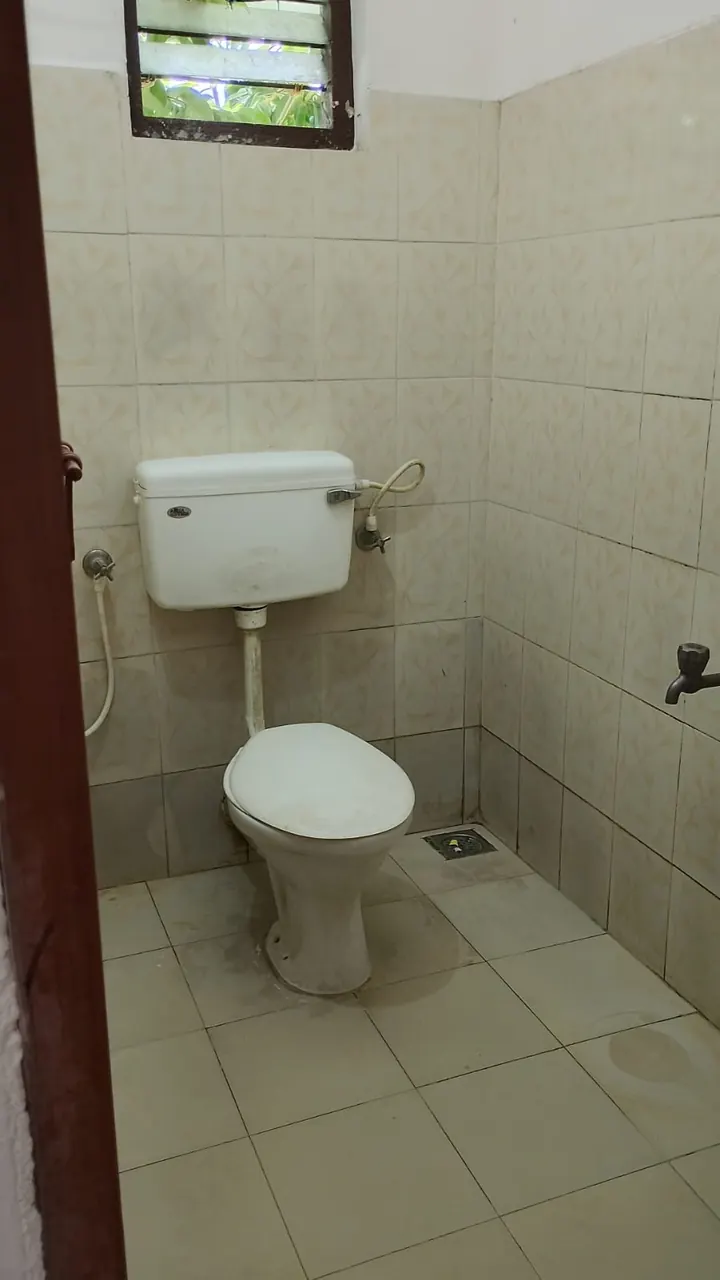 Tiled bathroom with western toilet at Ashraf Gents Hostel, Kalamassery