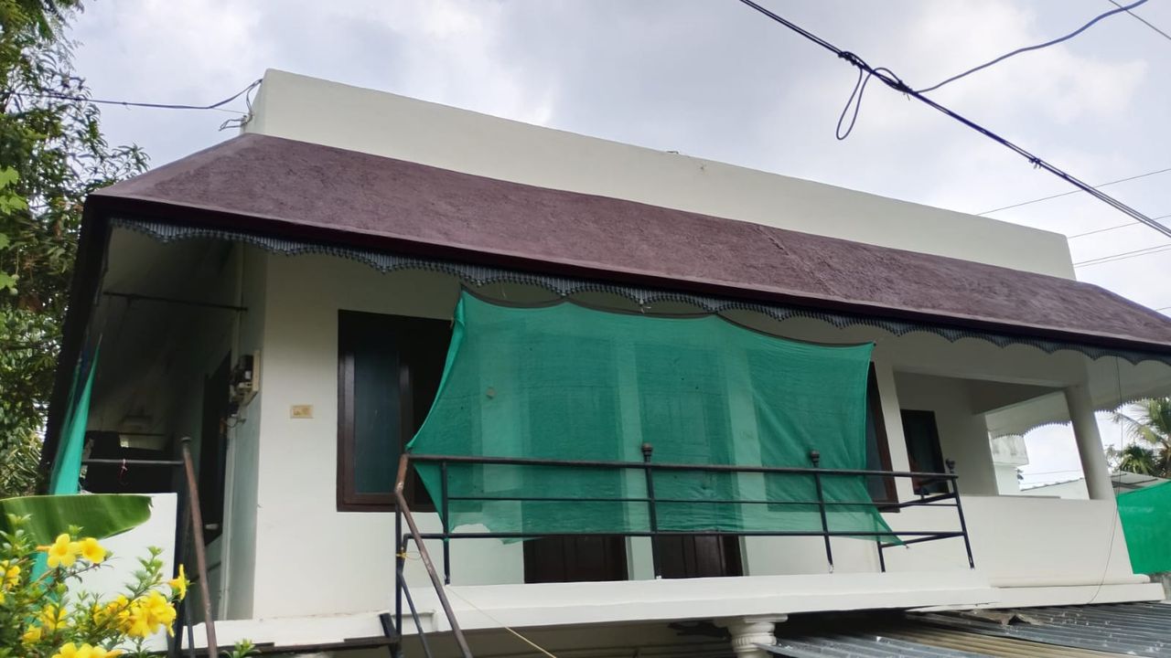 Front of the Ashraf Gents Hostel building with its upstairs balcony and green shade net, Kalamassery