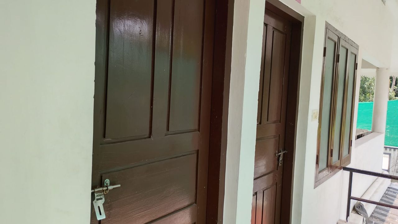 Corridor with wooden room doors at Ashraf Gents Hostel, Kalamassery