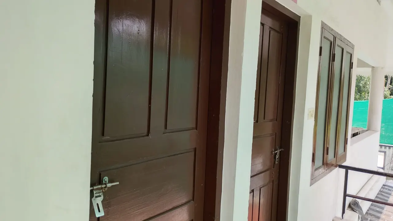Corridor with wooden room doors at Ashraf Gents Hostel, Kalamassery