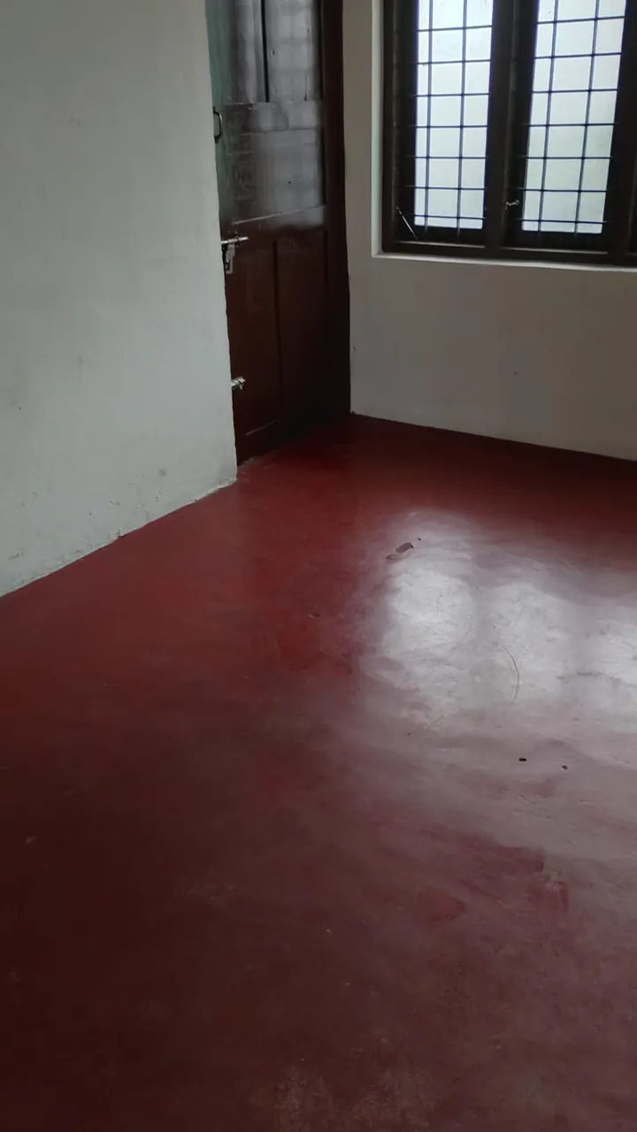 Room with red-oxide floor and window at Ashraf Gents Hostel, Kalamassery