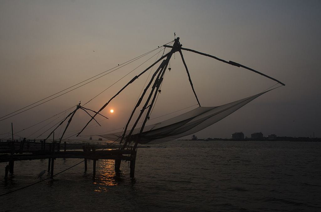 Silhouettes of Chinese fishing nets against the sunset at Fort Kochi
